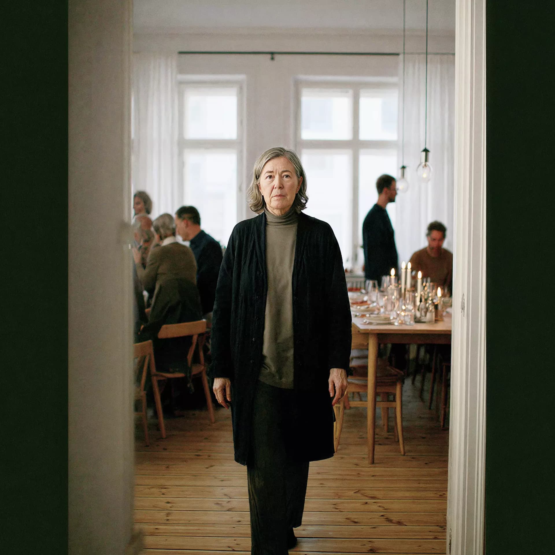 Woman who is going through a door at a social event with people sitting and standing at tables behind her